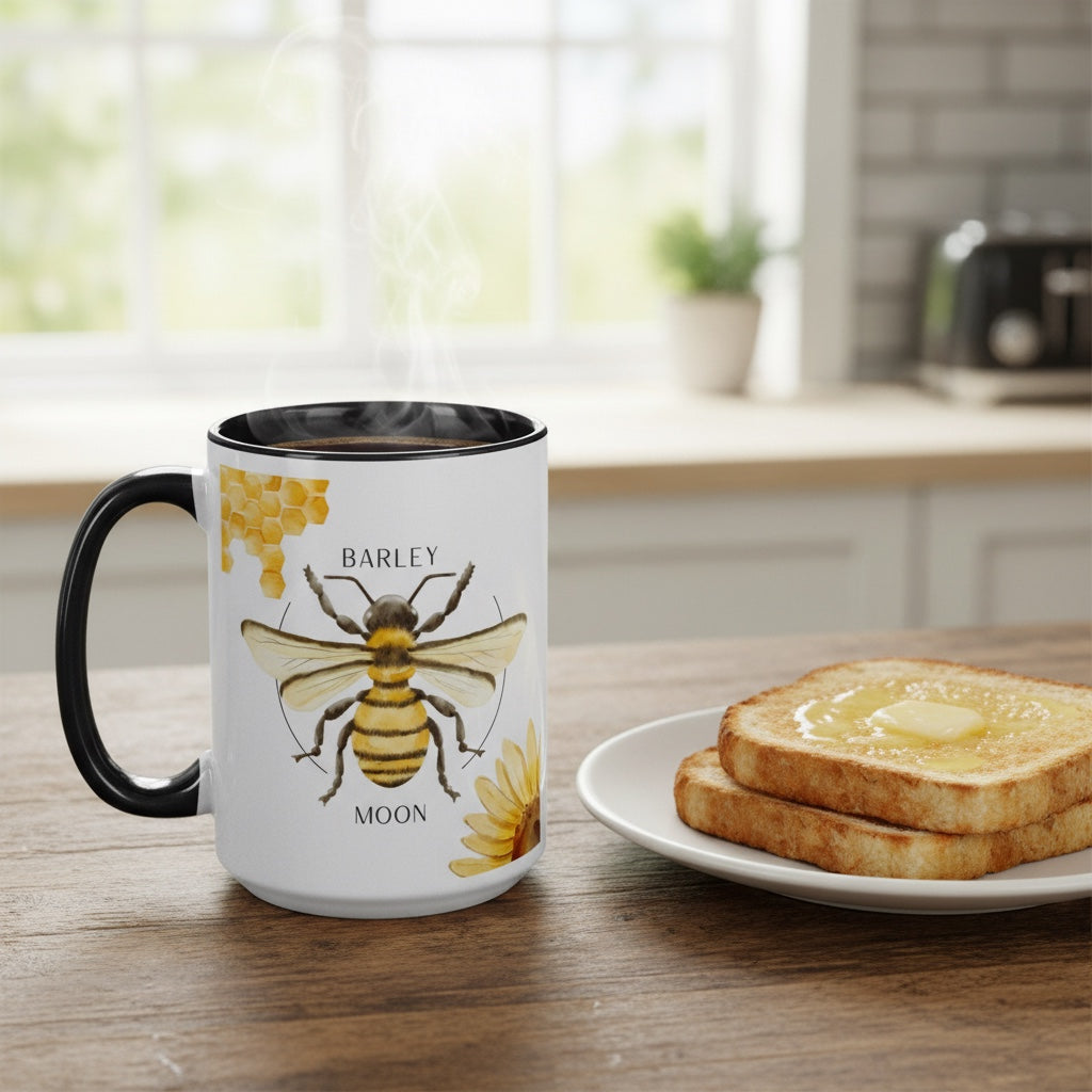 Barley Moon Botanicals 15oz ceramic mug with bee and flower design, black handle and interior, on a wooden table.