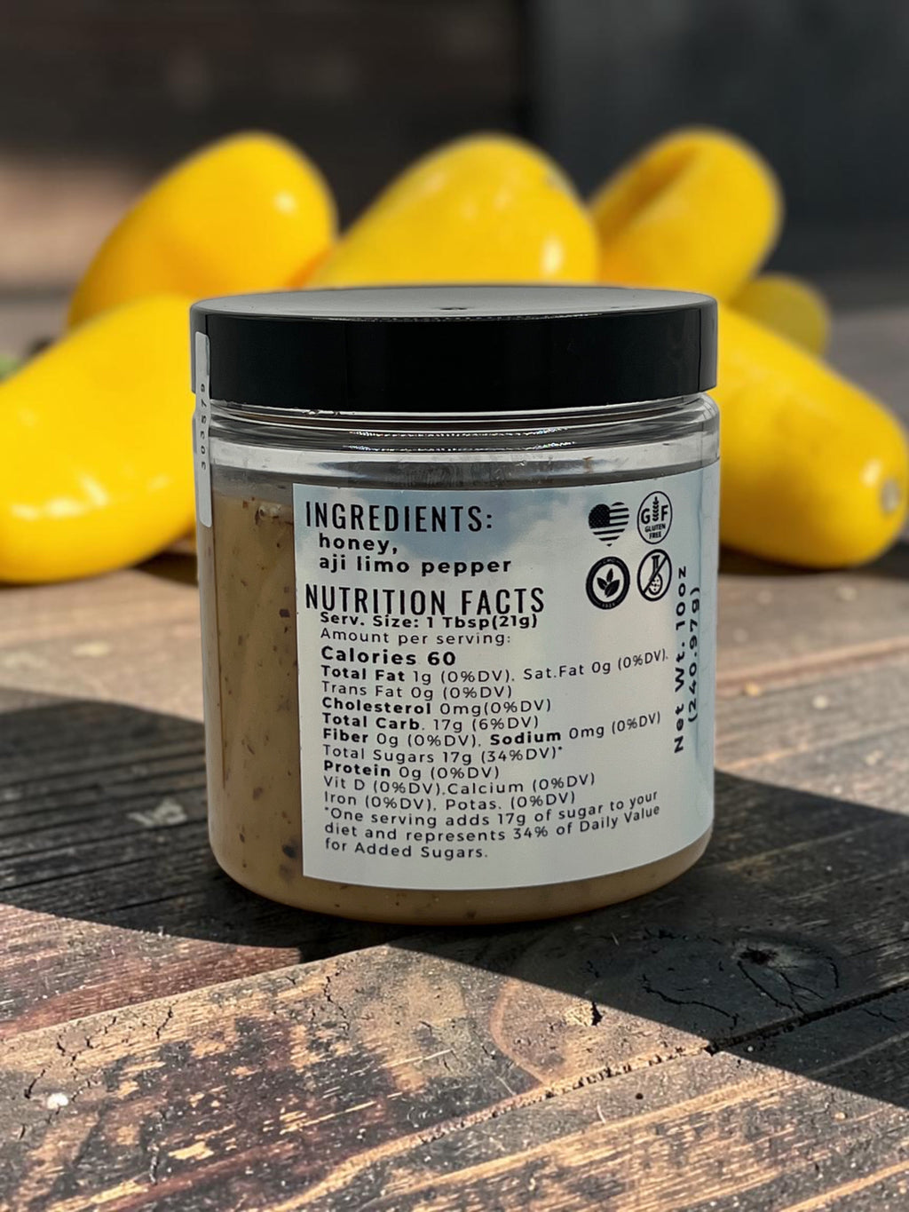 Barley Moon Botanicals Aji Limo Creamed Honey jar showing nutrition facts label with bright yellow peppers in background