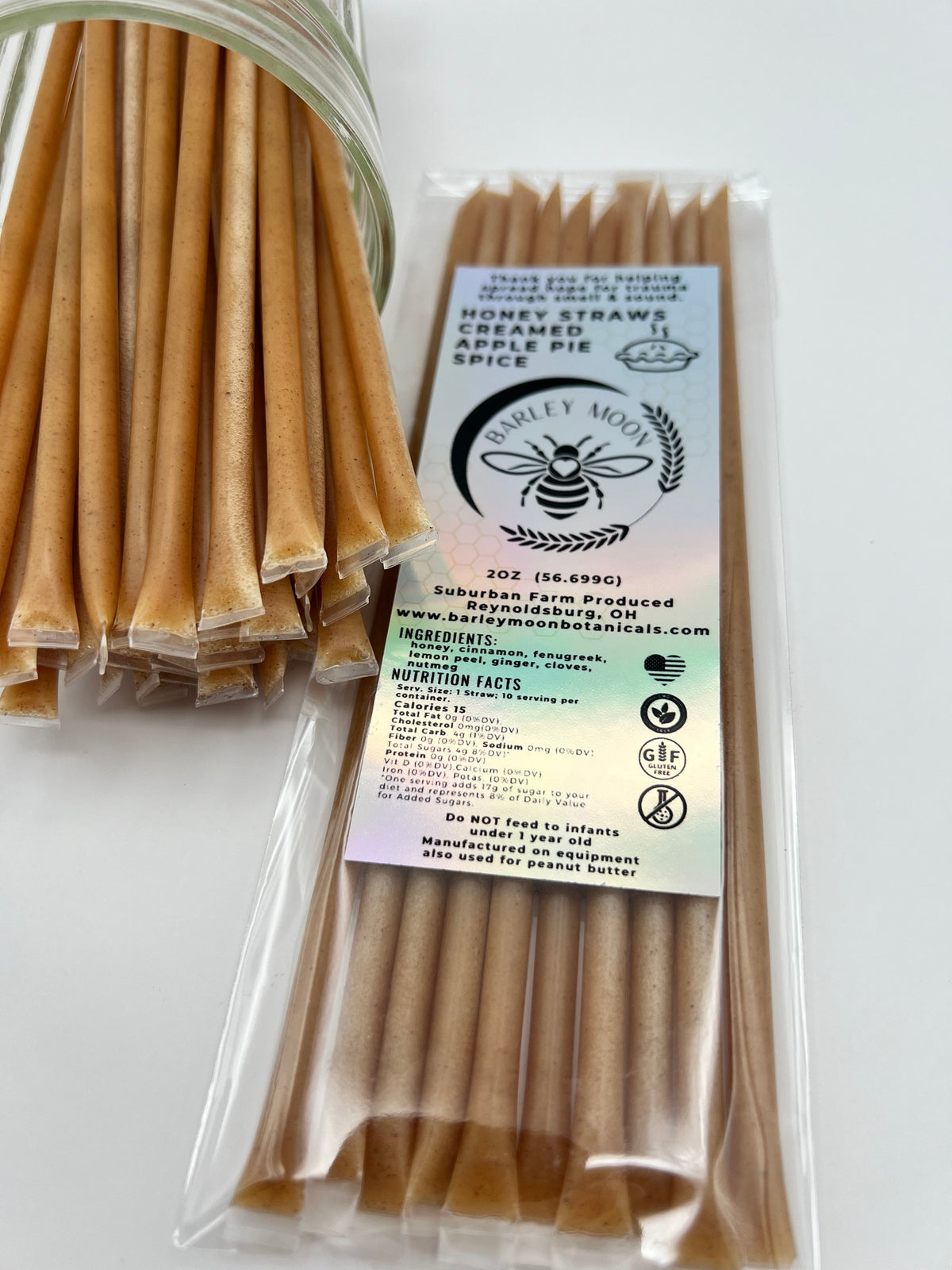 Barley Moon Botanicals Apple Pie Spice creamed honey straws in a glass jar and clear packaging on a white surface.
