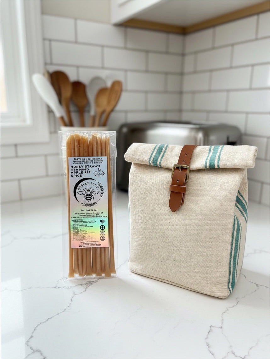 Barley Moon Botanicals Apple Pie Spice creamed honey straws next to a canvas lunch bag on a kitchen counter.