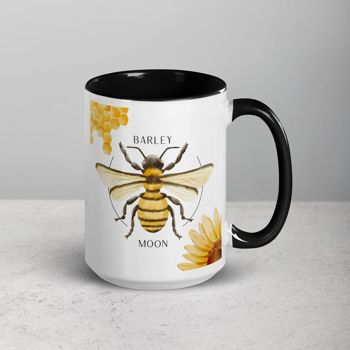 Barley Moon Botanicals 15oz ceramic mug with a bee, honeycomb, and flower design and a black handle and interior.