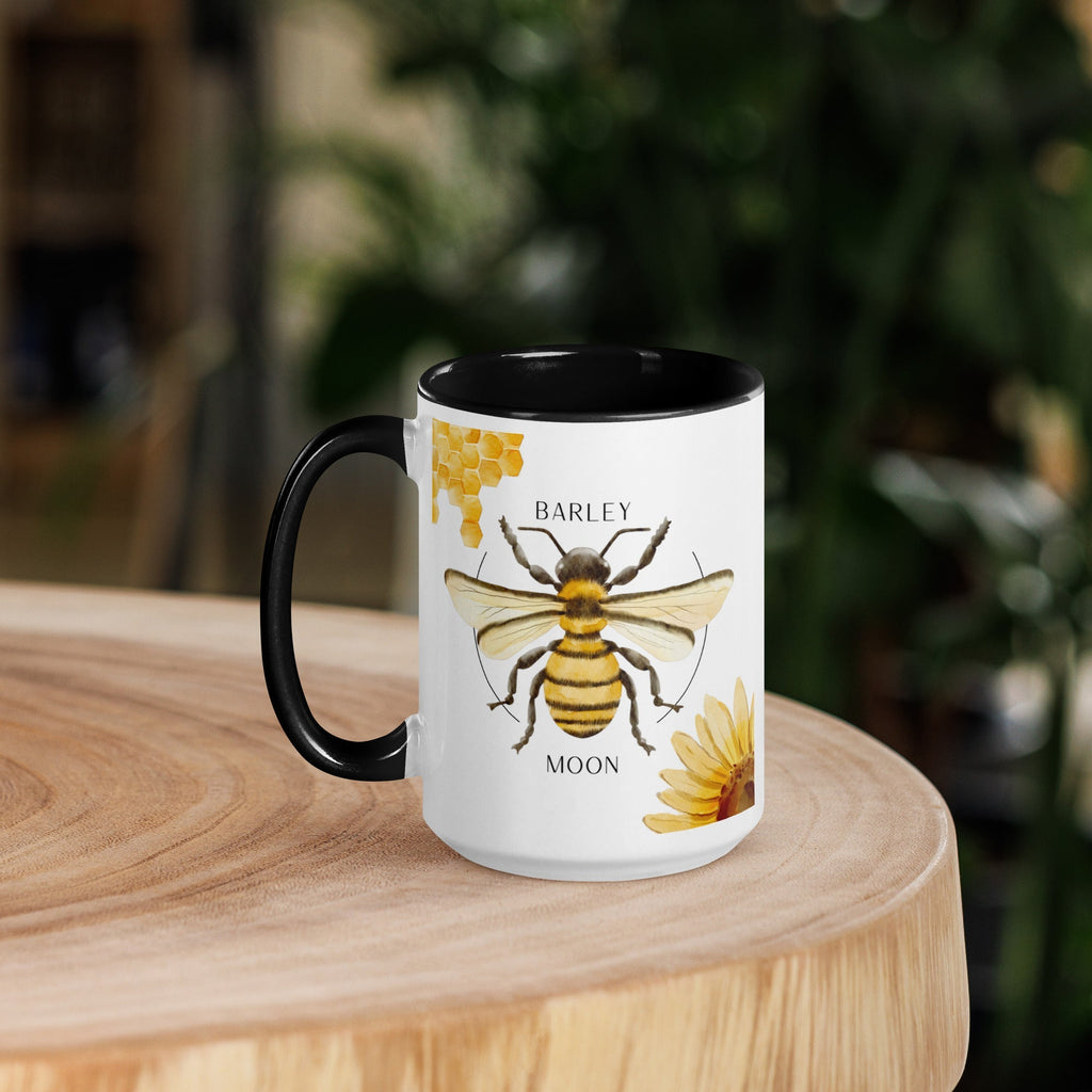 Barley Moon Botanicals 15oz ceramic mug with a bee and flower design, featuring a black handle and black interior.