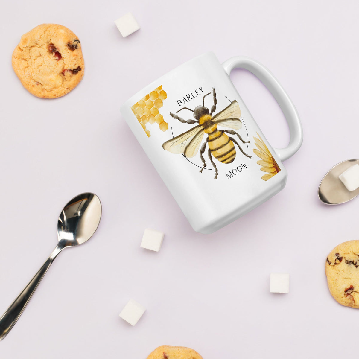 Barley Moon Botanicals 15 oz white ceramic mug with a bee, honeycomb, and flower illustration on a light background.
