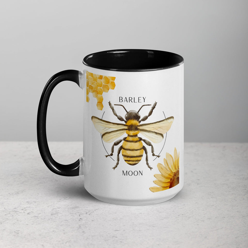 Barley Moon Botanicals 15oz ceramic mug featuring a bee, honeycomb, and flower design with a black handle and interior.