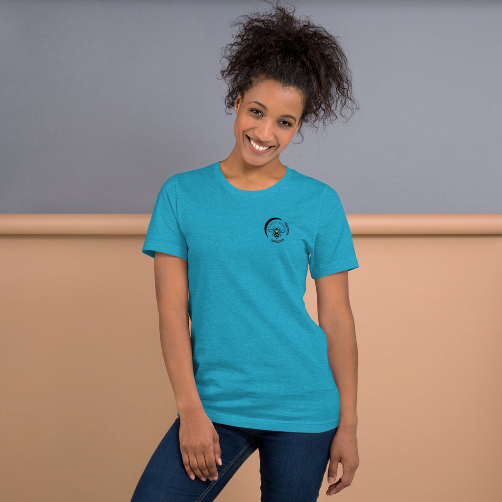 A smiling woman wearing a soft blue Barley Moon Botanicals t-shirt with a black bee and crescent moon logo.