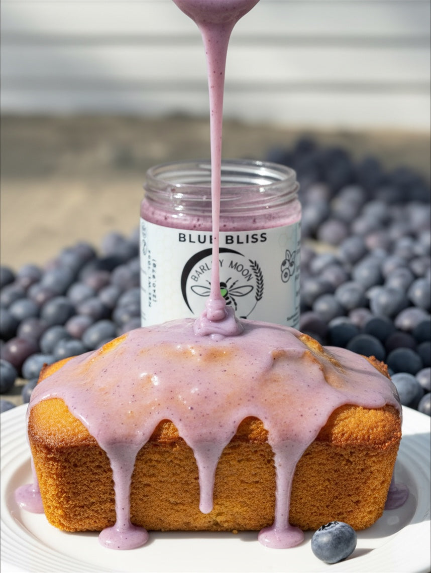 Barley Moon Botanicals Blue Bliss blueberry creamed honey drizzled over a golden loaf cake surrounded by fresh berries