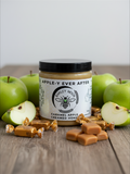 Barley Moon Botanicals Apple-y Ever After creamed honey jar surrounded by fresh green apples and caramel candies.