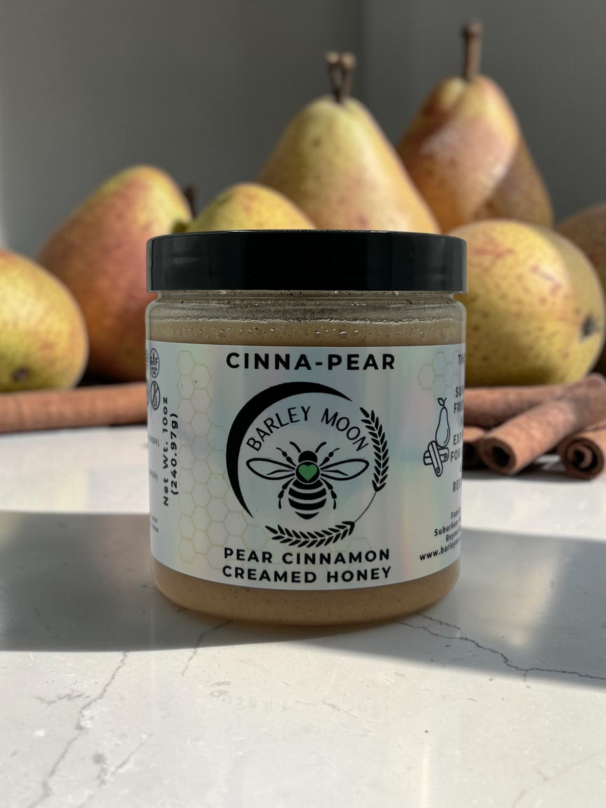 Barley Moon Botanicals Cinna-Pear creamed honey jar with cinnamon sticks and fresh pears in the background