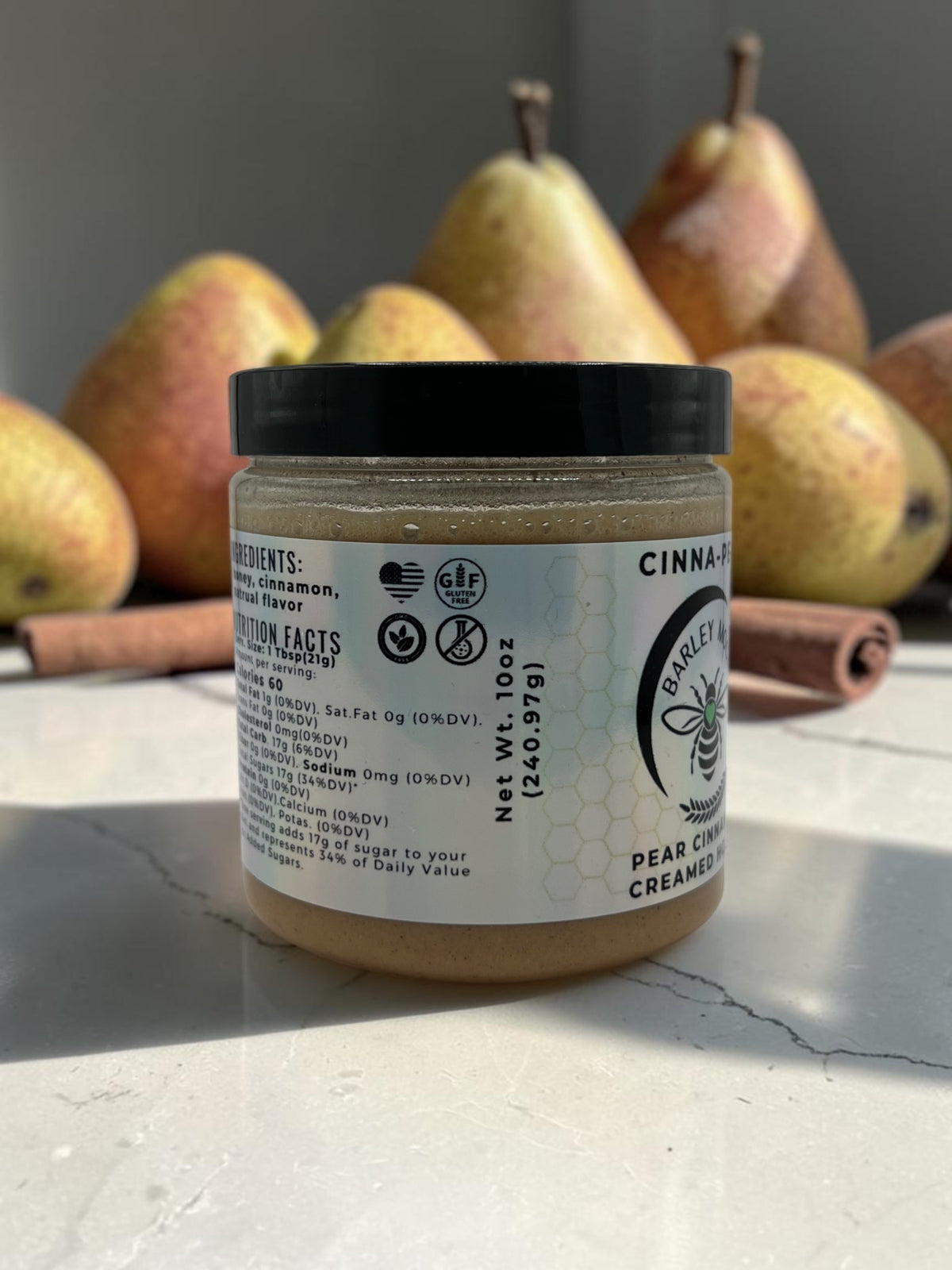 Barley Moon Botanicals Cinna-Pear creamed honey jar with cinnamon sticks and fresh pears in the background