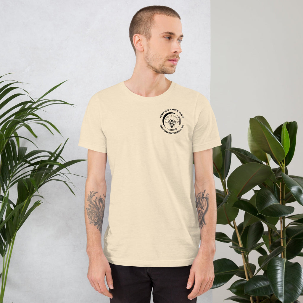 Barley Moon Botanicals unisex cream cotton t-shirt with a small black bee logo on the chest, worn by a man.