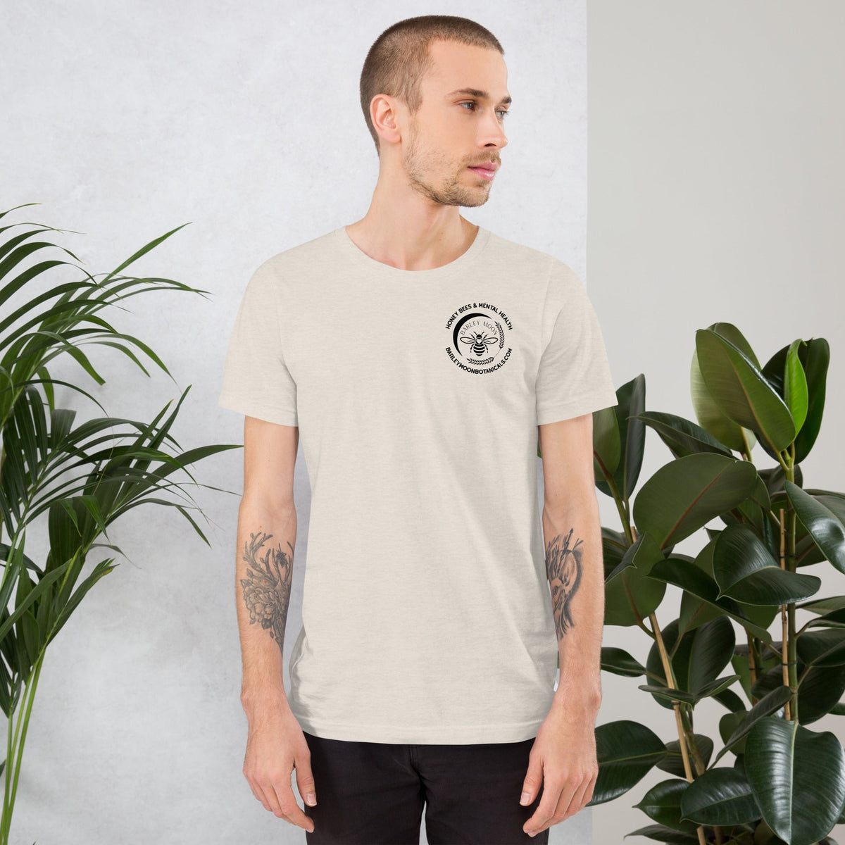 Man wearing a Barley Moon Botanicals cream cotton t-shirt with a small bee and mental health logo on the chest
