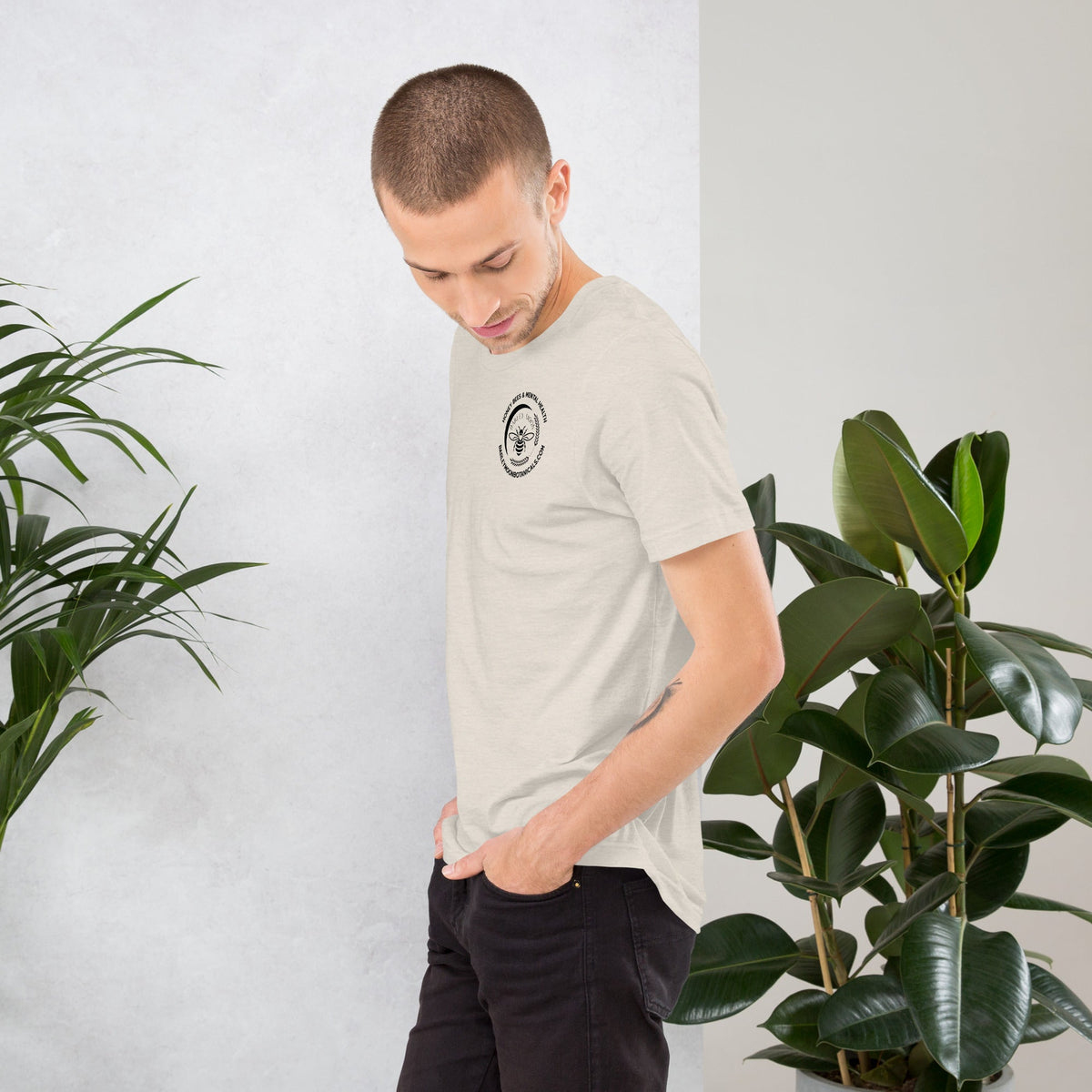 Barley Moon Botanicals unisex t-shirt in light beige cotton with a small bee graphic on the chest, worn by a man.