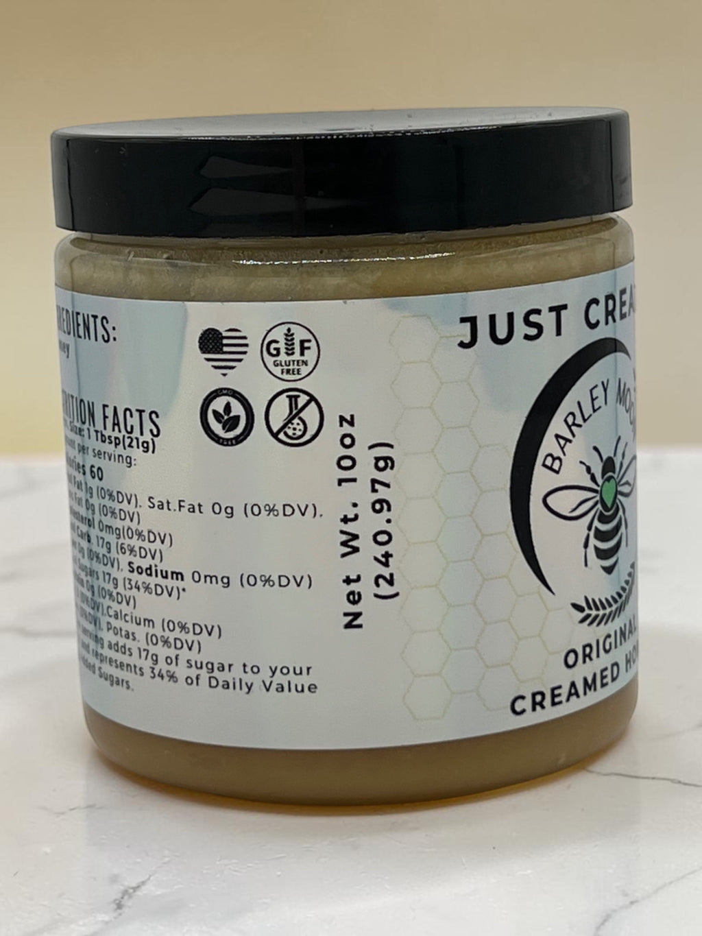 Barley Moon Botanicals Just Creamy original creamed honey in a 10oz glass jar with a black lid on a white surface.