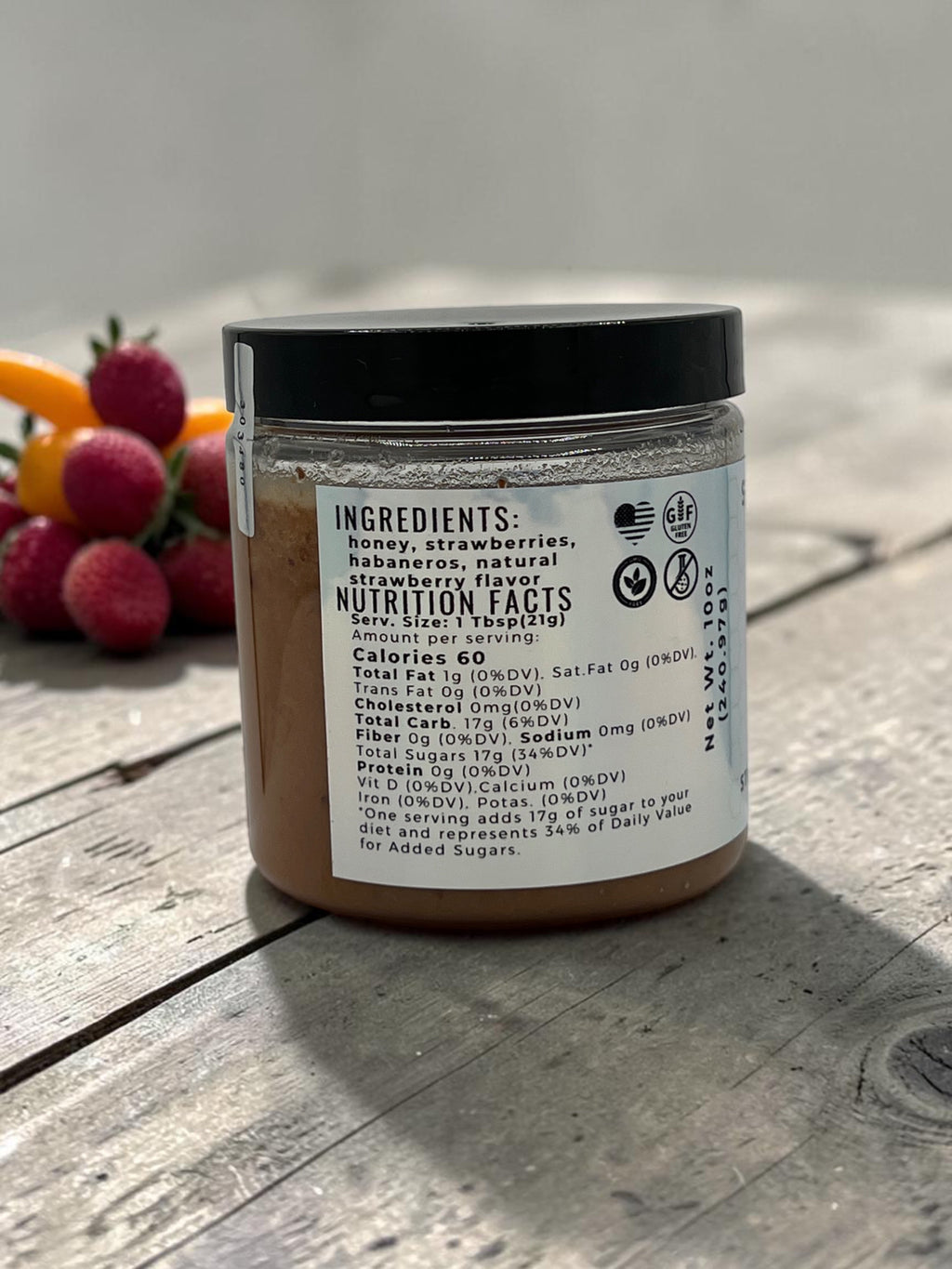 Barley Moon Botanicals Strawbanero creamed honey jar showing nutrition facts label with fresh strawberries in background