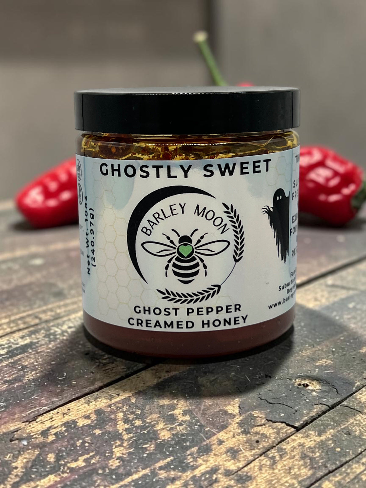 Barley Moon Botanicals Ghostly Sweet ghost pepper infused creamed honey in a glass jar on a rustic wooden surface.