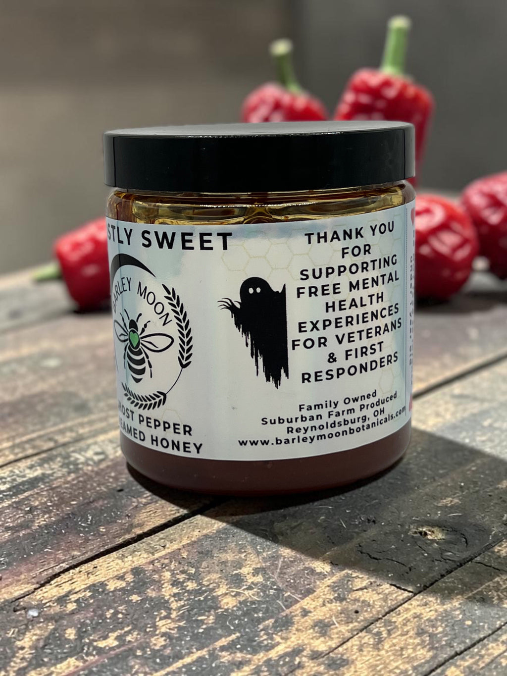 Barley Moon Botanicals Ghostly Sweet ghost pepper infused honey jar with a ghost graphic on a rustic wooden table