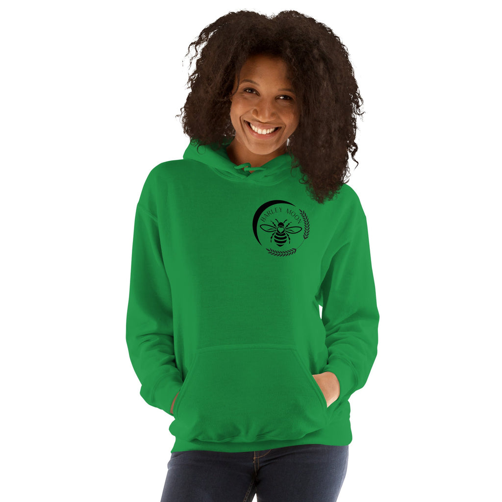 Woman wearing a green Barley Moon Botanicals unisex hoodie with a black bee and crescent moon logo on the chest.