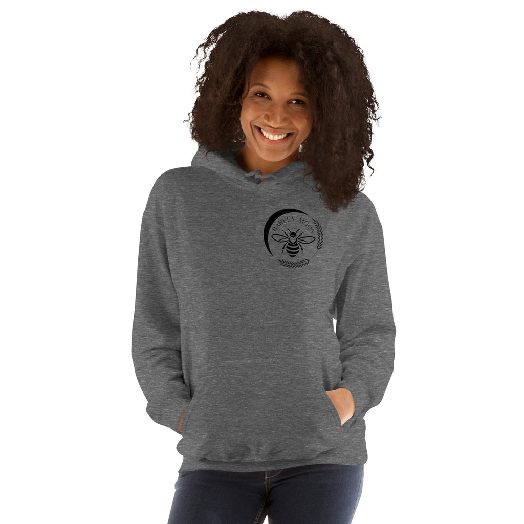 A woman wearing a Barley Moon Botanicals grey heather unisex hoodie with a black bee and crescent moon chest logo.