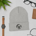Barley Moon Botanicals grey cuffed beanie with a black bee and moon logo, displayed on a flat lay desk surface.