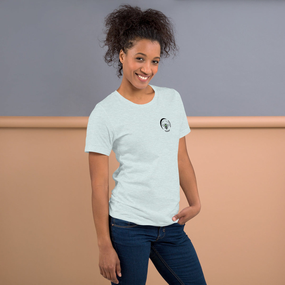 A woman wearing a Barley Moon Botanicals light grey t-shirt with a small black bee and crescent moon logo on the chest.