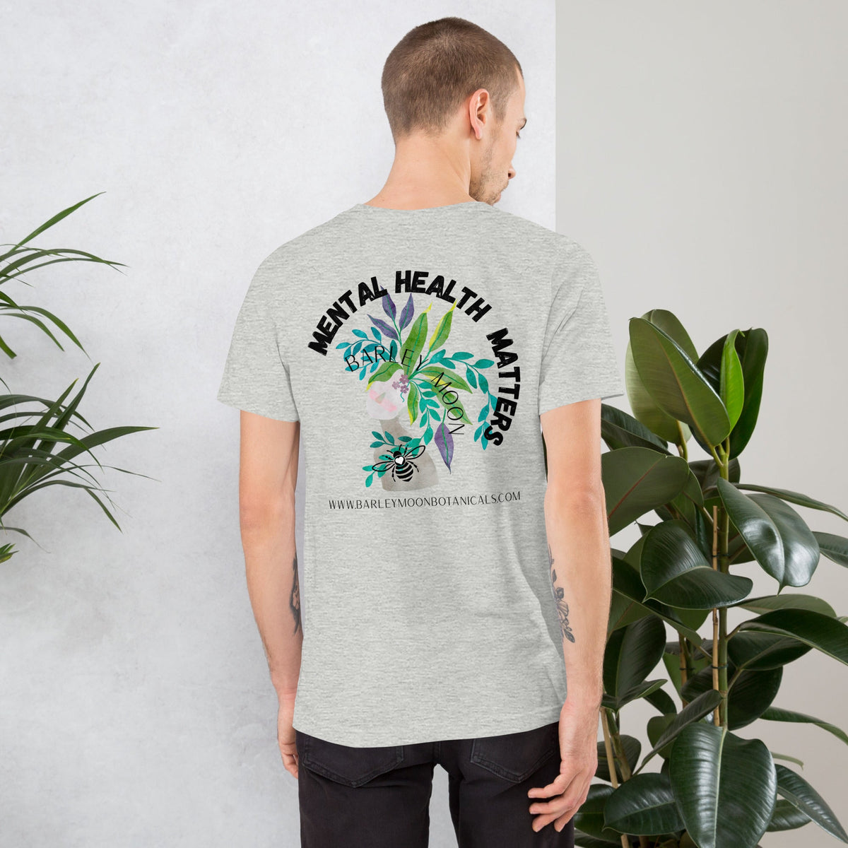 Man wearing a grey Barley Moon Botanicals unisex t-shirt with a botanical Mental Health Matters bee graphic on the back