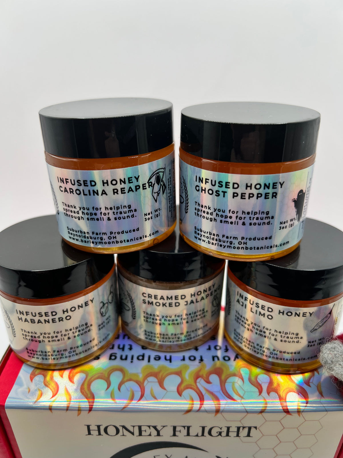 Barley Moon Botanicals Hot Box Honey Flight featuring five jars of spicy infused honey in a red gift box with a felt bee