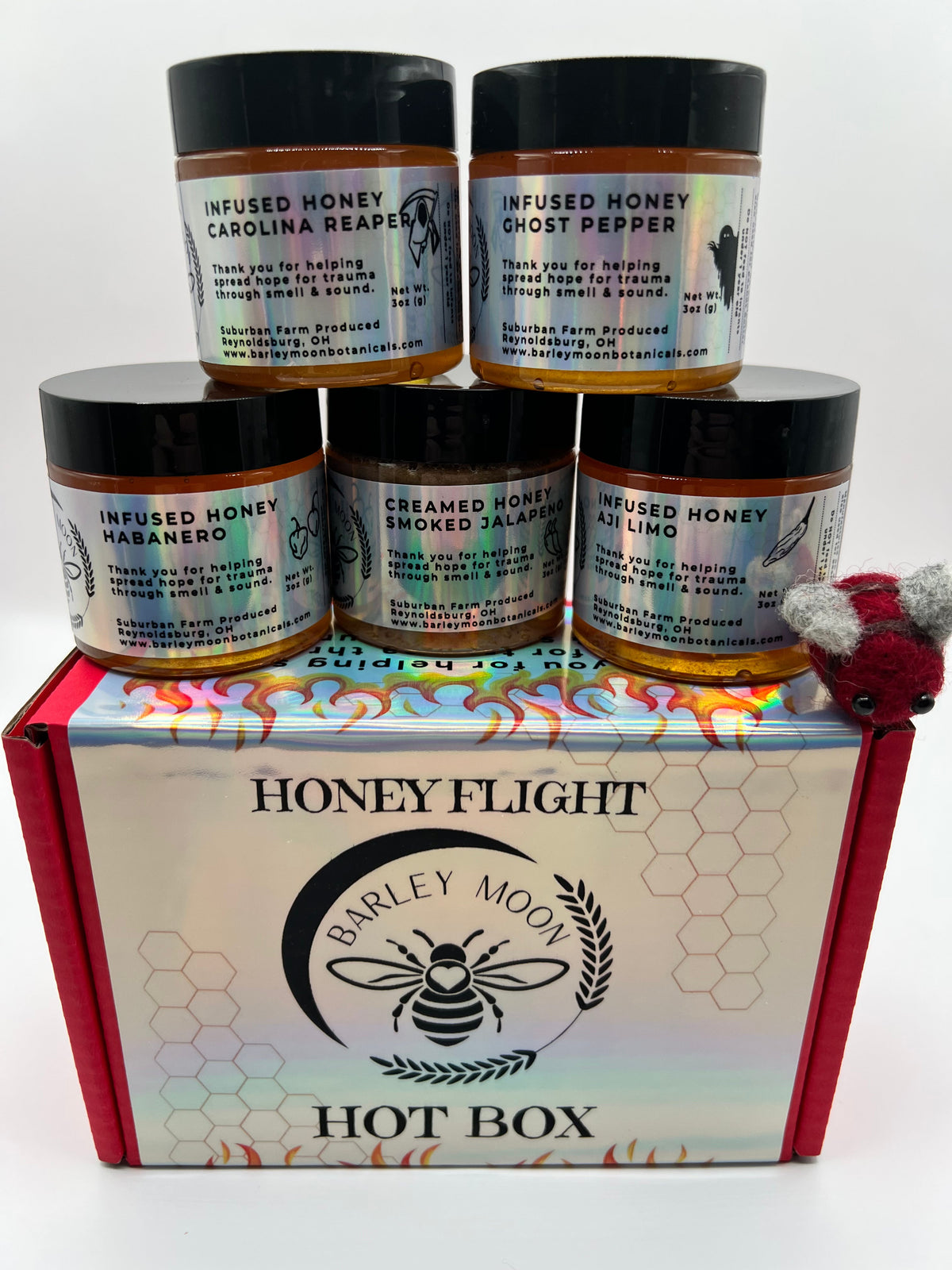 Barley Moon Botanicals Hot Box Honey Flight featuring five jars of spicy infused honey in a red gift box with a felt bee
