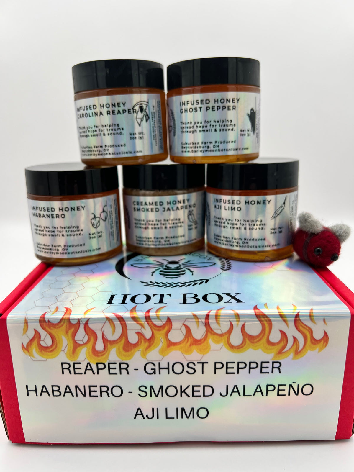Barley Moon Botanicals Hot Box Honey Flight featuring five jars of spicy infused honey in a red gift box with a felt bee