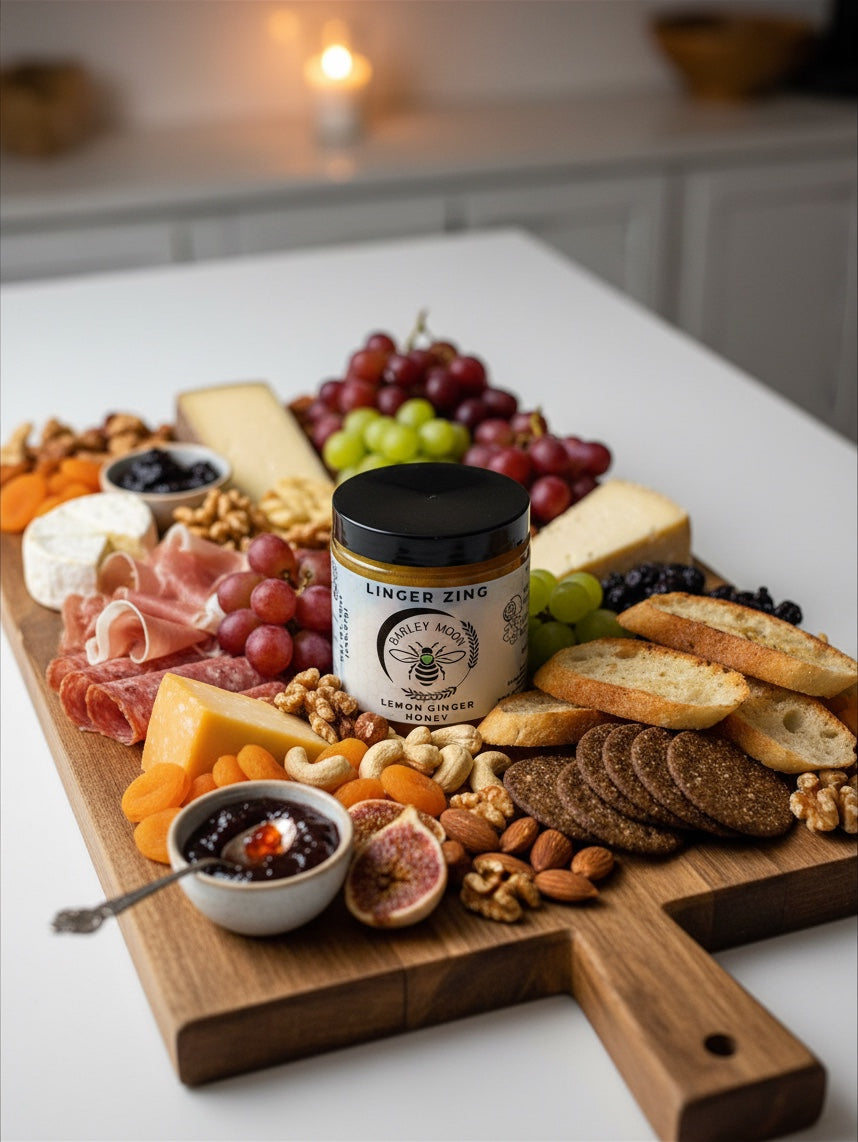 Barley Moon Botanicals Linger Zing lemon ginger honey jar centered on a gourmet charcuterie board with cheese and fruit