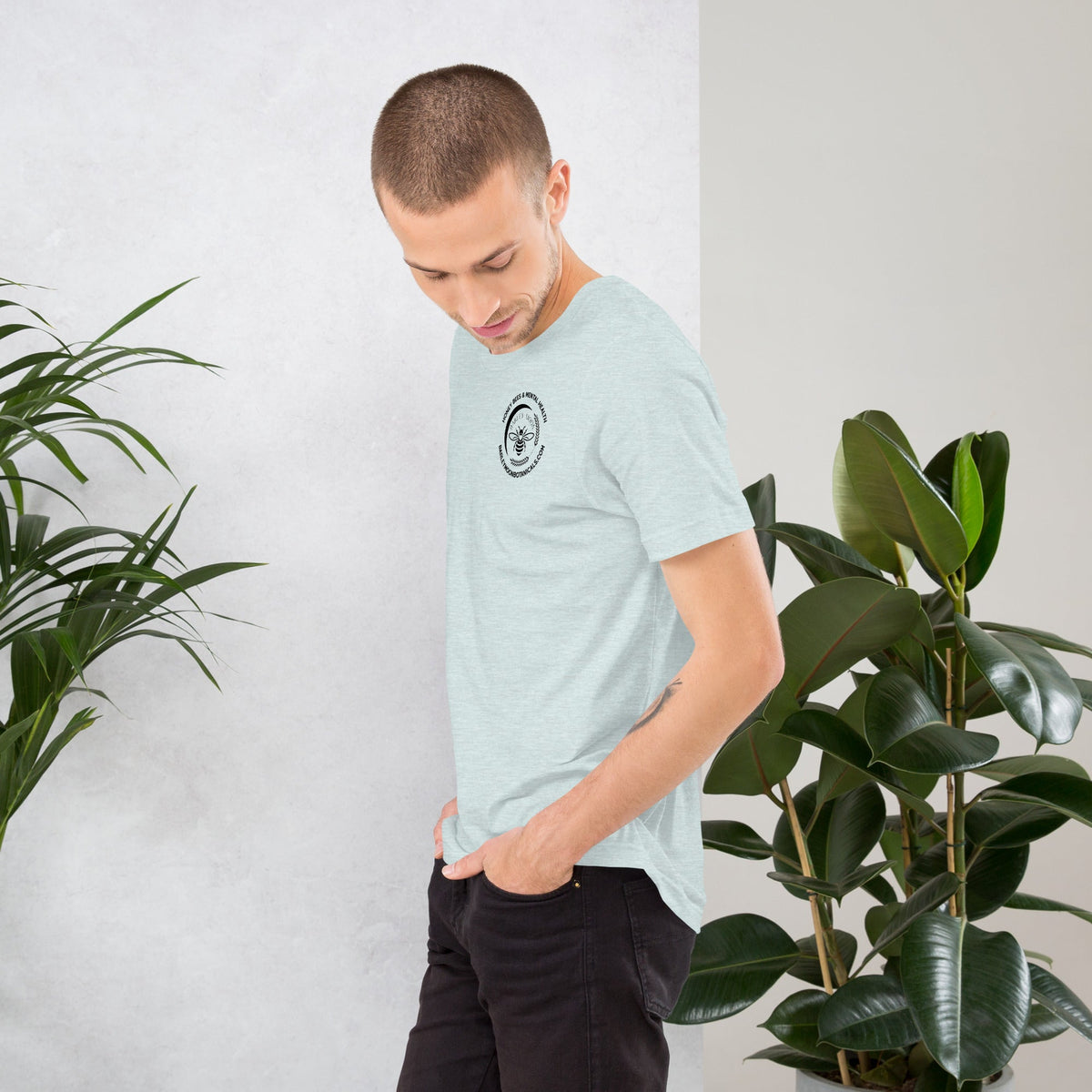 A man wearing a light blue Barley Moon Botanicals unisex t-shirt with a small bee logo and mental health message.