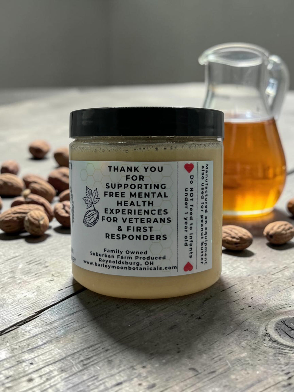 Barley Moon Botanicals MapeCozy maple pecan creamed honey jar on a wooden table with pecans and a glass pitcher