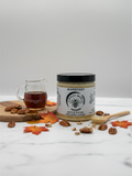 Barley Moon Botanicals MapeCozy maple pecan creamed honey jar on a marble surface with pecans and autumn leaves