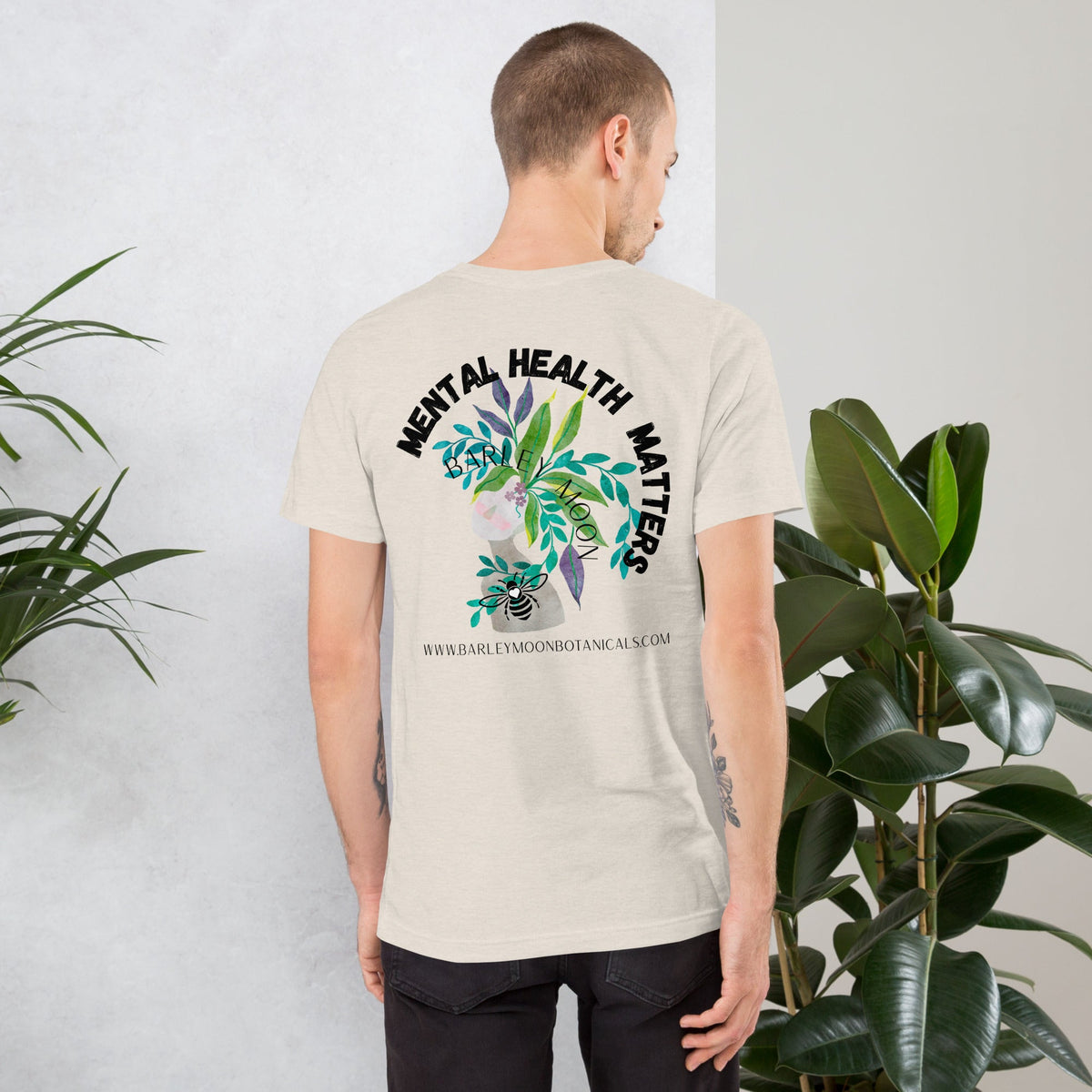 Man wearing a Barley Moon Botanicals cream t-shirt with a Mental Health Matters botanical bee graphic on the back.