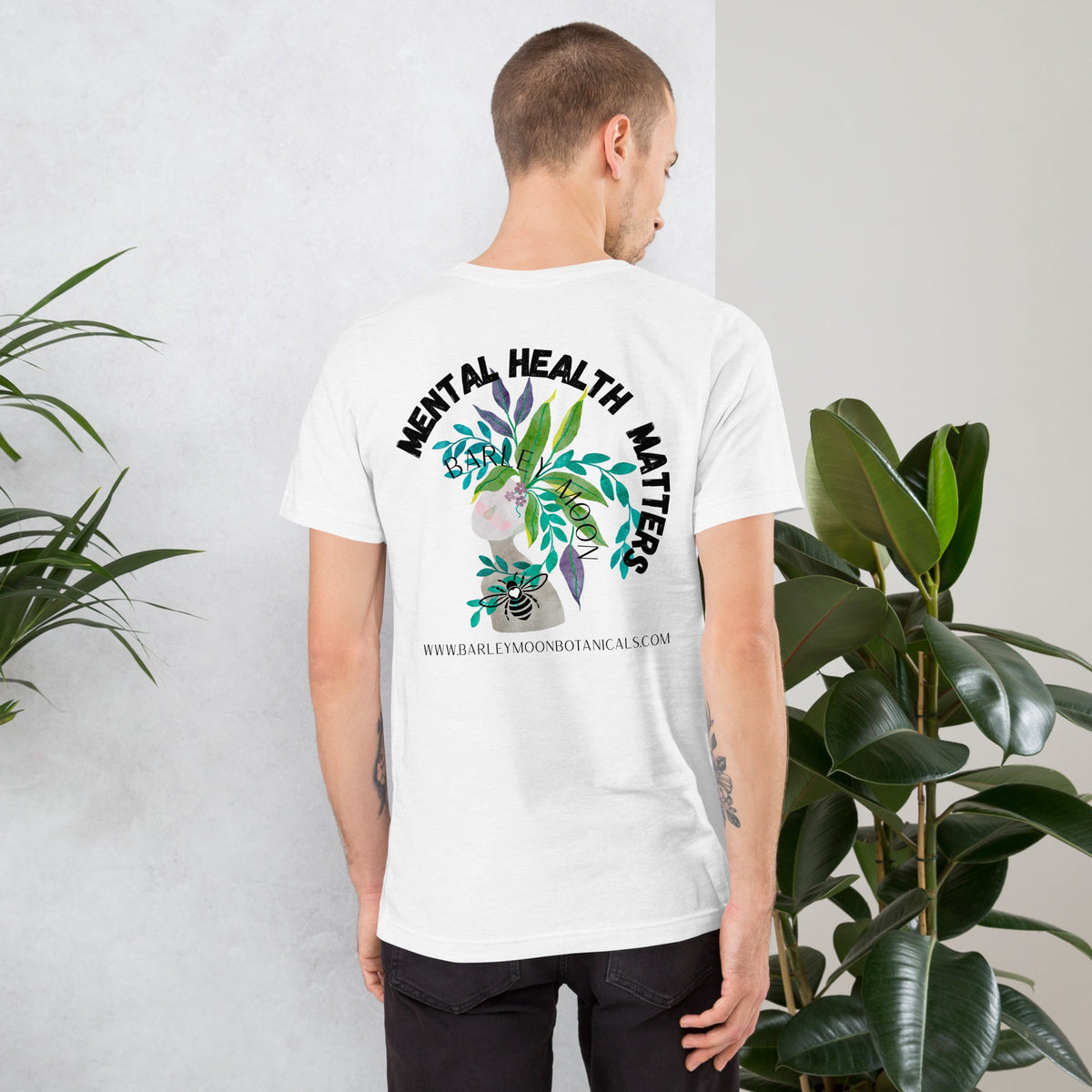 Man wearing a white Barley Moon Botanicals unisex t-shirt with a Mental Health Matters botanical bee back graphic.