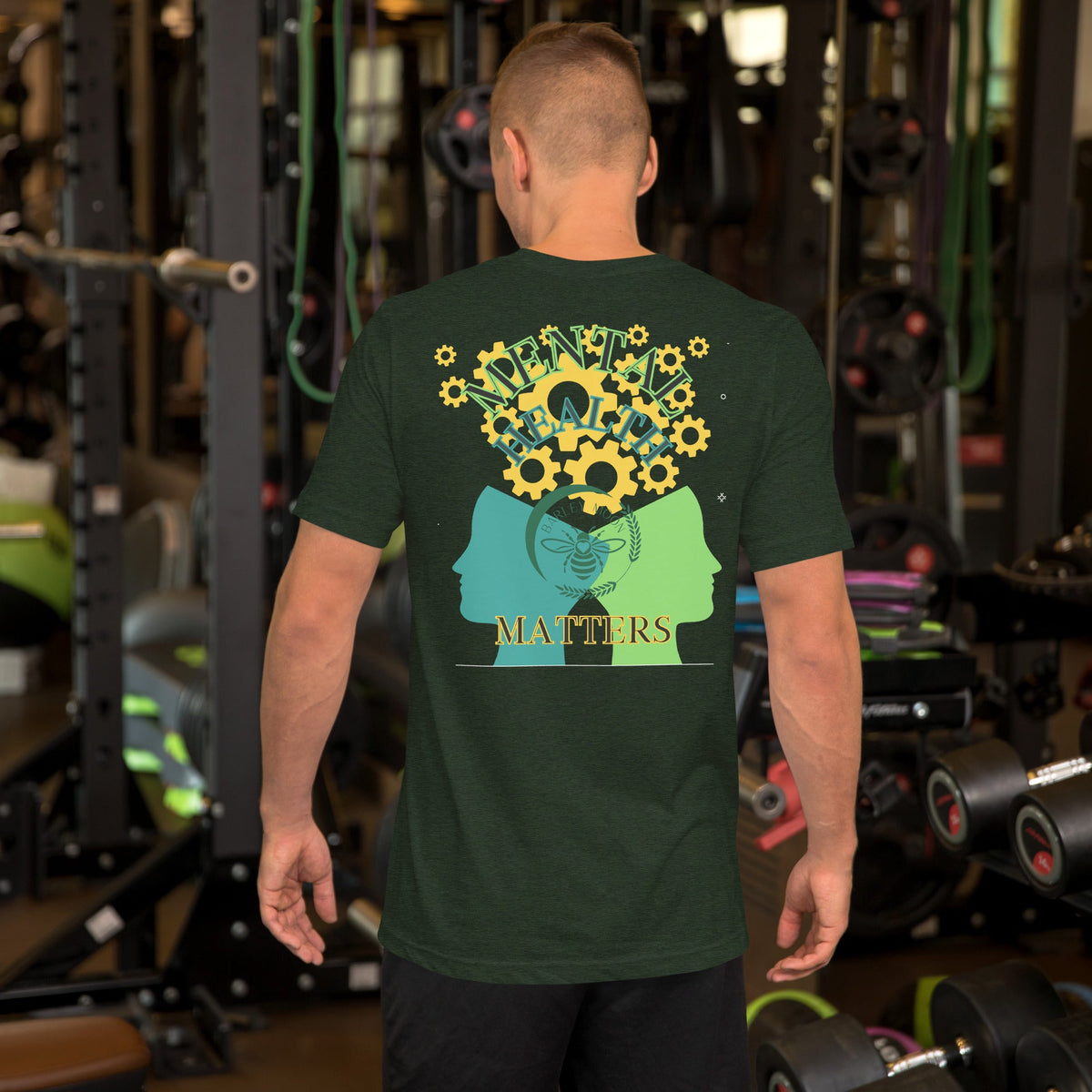 Man wearing a dark green Barley Moon Botanicals unisex t-shirt with a mental health graphic on the back in a gym.