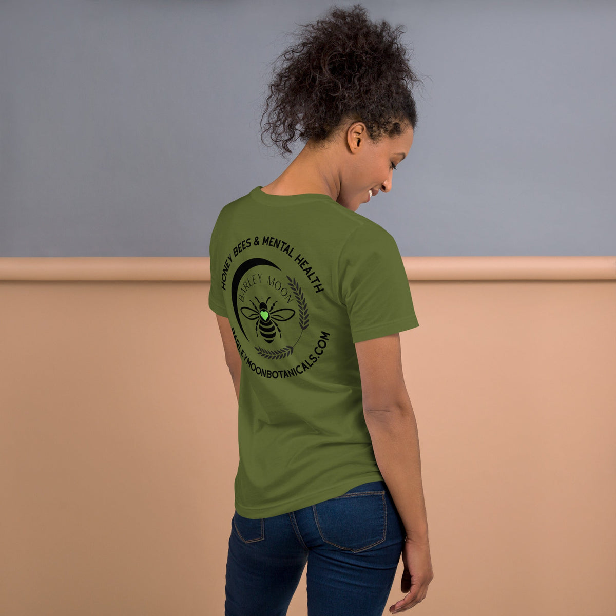 Barley Moon Botanicals olive green t-shirt with Honey Bees & Mental Health logo on the back worn by a woman