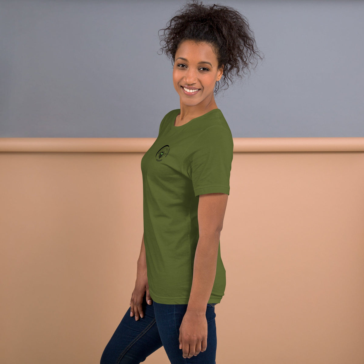 Barley Moon Botanicals olive green cotton t-shirt with bee and crescent moon logo worn by a smiling woman