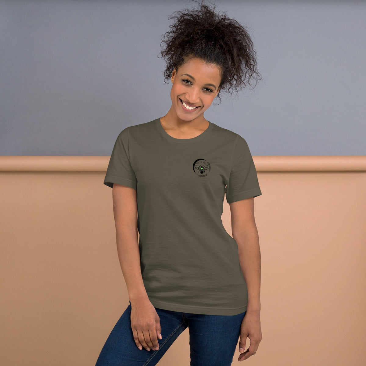 A woman wearing a Barley Moon Botanicals olive green cotton t-shirt with a black bee and crescent moon logo.