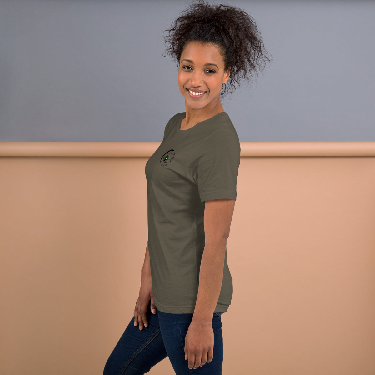 A woman wearing a Barley Moon Botanicals olive green cotton t-shirt with a small bee and crescent moon logo.