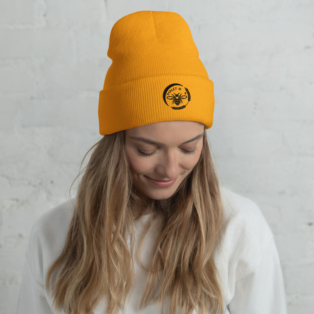 Barley Moon Botanicals cuffed beanie in bright orange with a black bee and moon logo worn by a woman