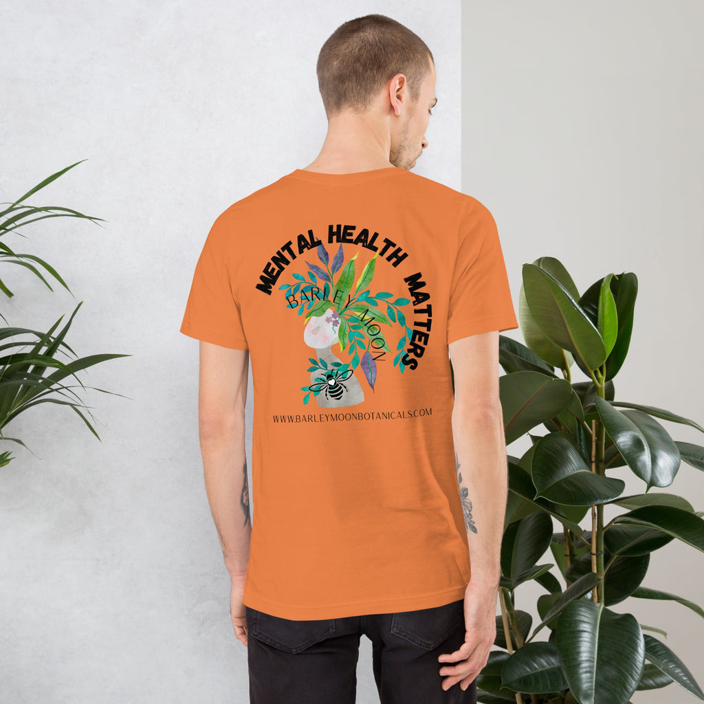 Man wearing a Barley Moon Botanicals orange unisex t-shirt with Mental Health Matters botanical bee graphic on back
