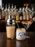 Barley Moon Botanicals Peachy Ghost creamed honey jar next to a cocktail shaker and a martini glass with a chili
