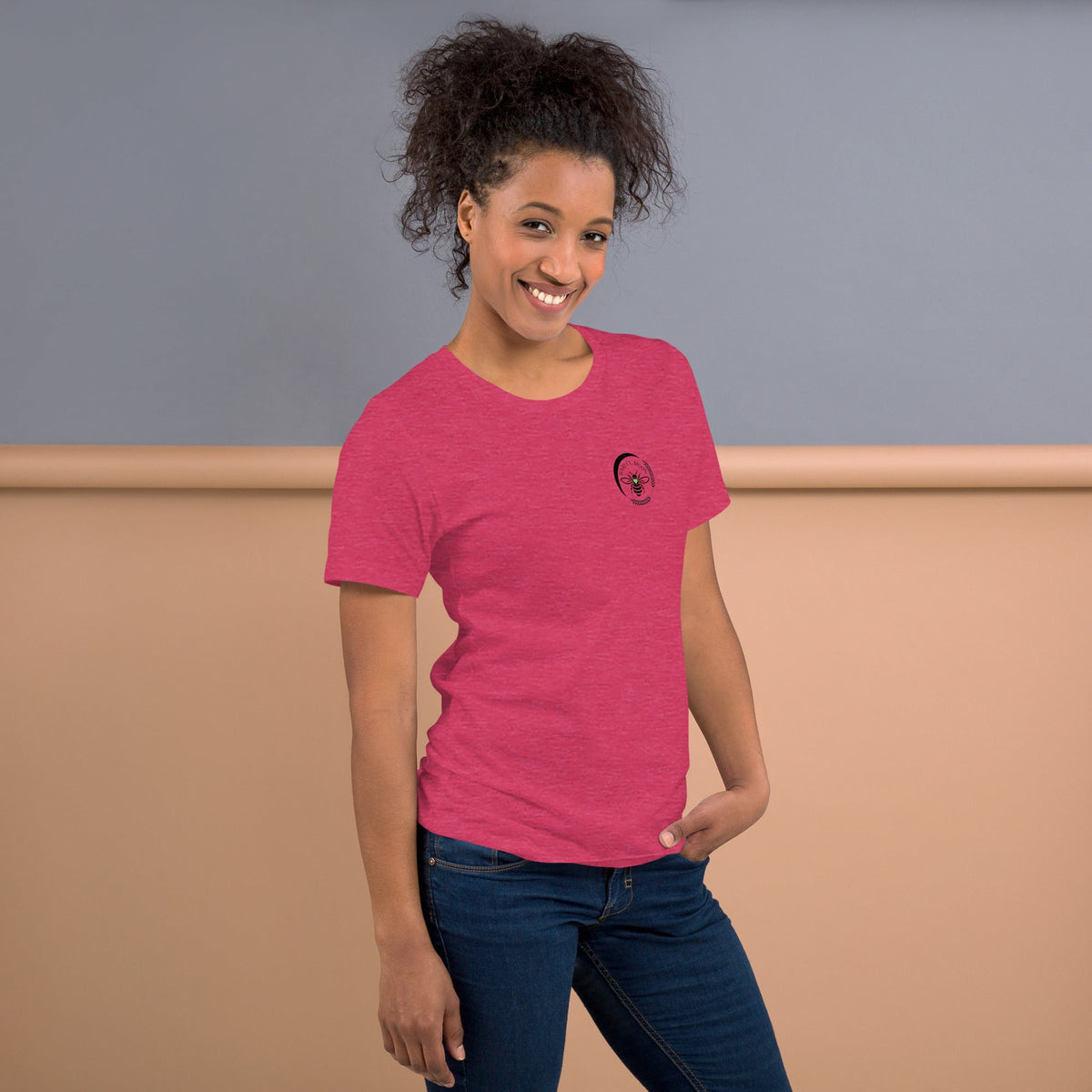 Woman wearing a pink Barley Moon Botanicals t-shirt with a black bee and crescent moon logo on the chest.