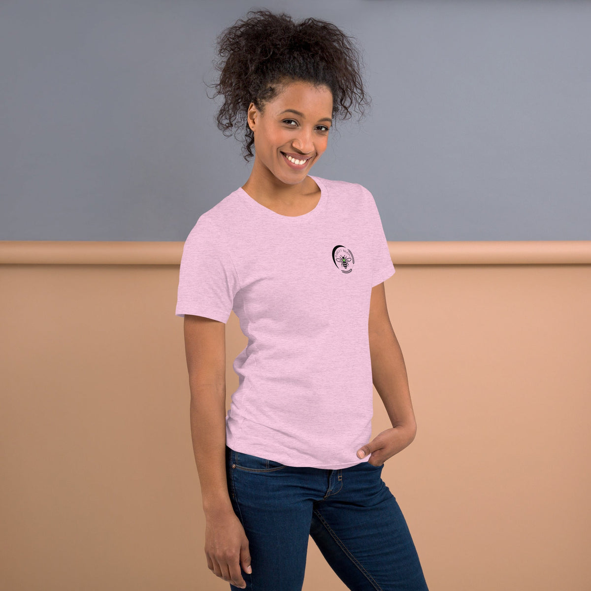 Barley Moon Botanicals light pink t-shirt with a small black bee and crescent moon logo on a smiling woman