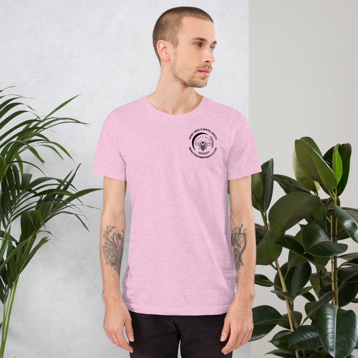 Barley Moon Botanicals unisex pink cotton t-shirt with a small black bee logo on the chest worn by a man.