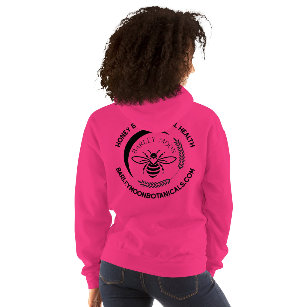 Woman wearing a bright pink Barley Moon Botanicals unisex hoodie with a black bee and moon logo on the back