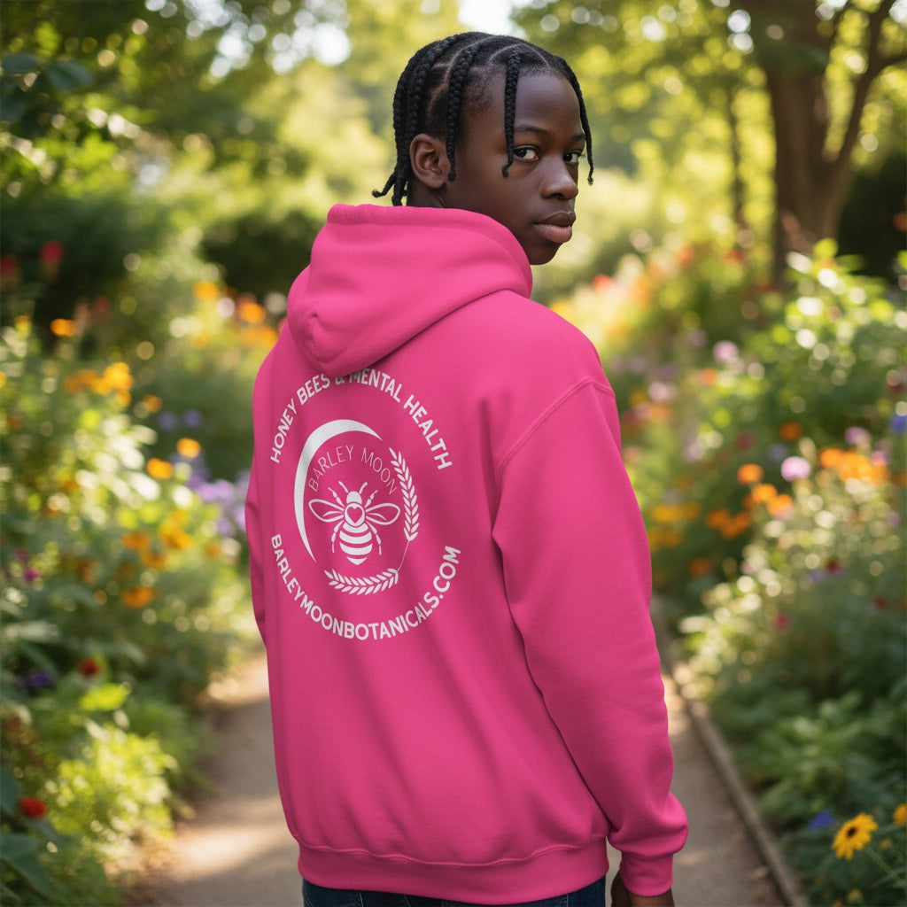 Barley Moon Botanicals pink unisex hoodie with Honey Bees and Mental Health logo worn by a person in a garden.