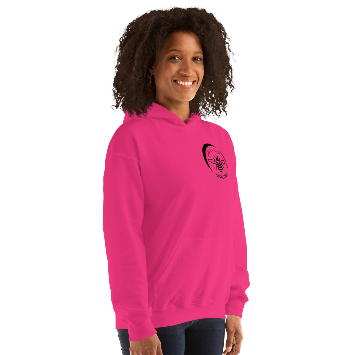 A woman wearing a bright pink Barley Moon Botanicals unisex hoodie with a black bee and crescent moon logo on the chest