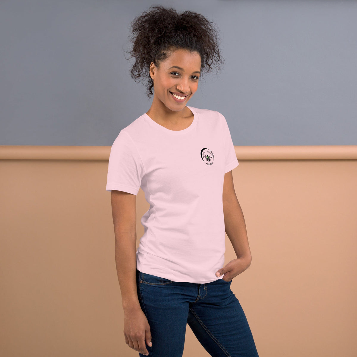 Woman wearing a light pink Barley Moon Botanicals t-shirt with a small black bee and crescent moon logo on the chest.