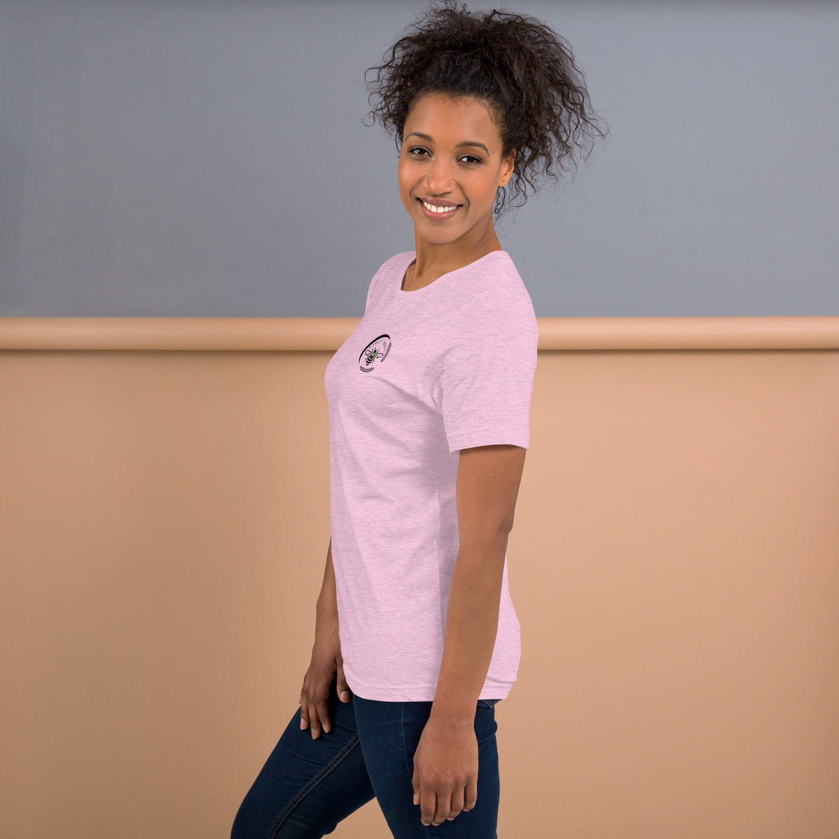 A woman wearing a light pink Barley Moon Botanicals t-shirt with a bee and crescent moon logo on the chest.